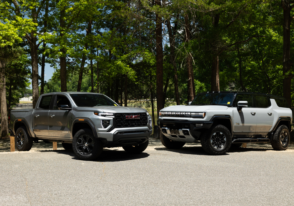 GMC Hummer EV and Canyon parked in front of trees