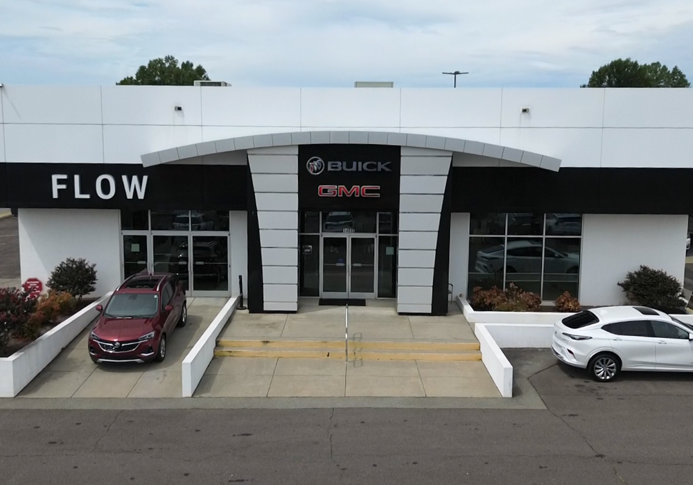 Flow Buick GMC of Greensboro dealership storefront with two cars parked in front